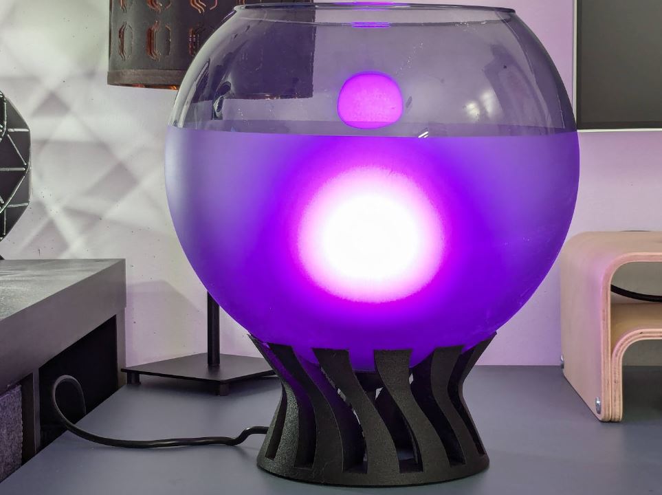 the lamp as seen on a desk, showing a hue bulb inside with purple light