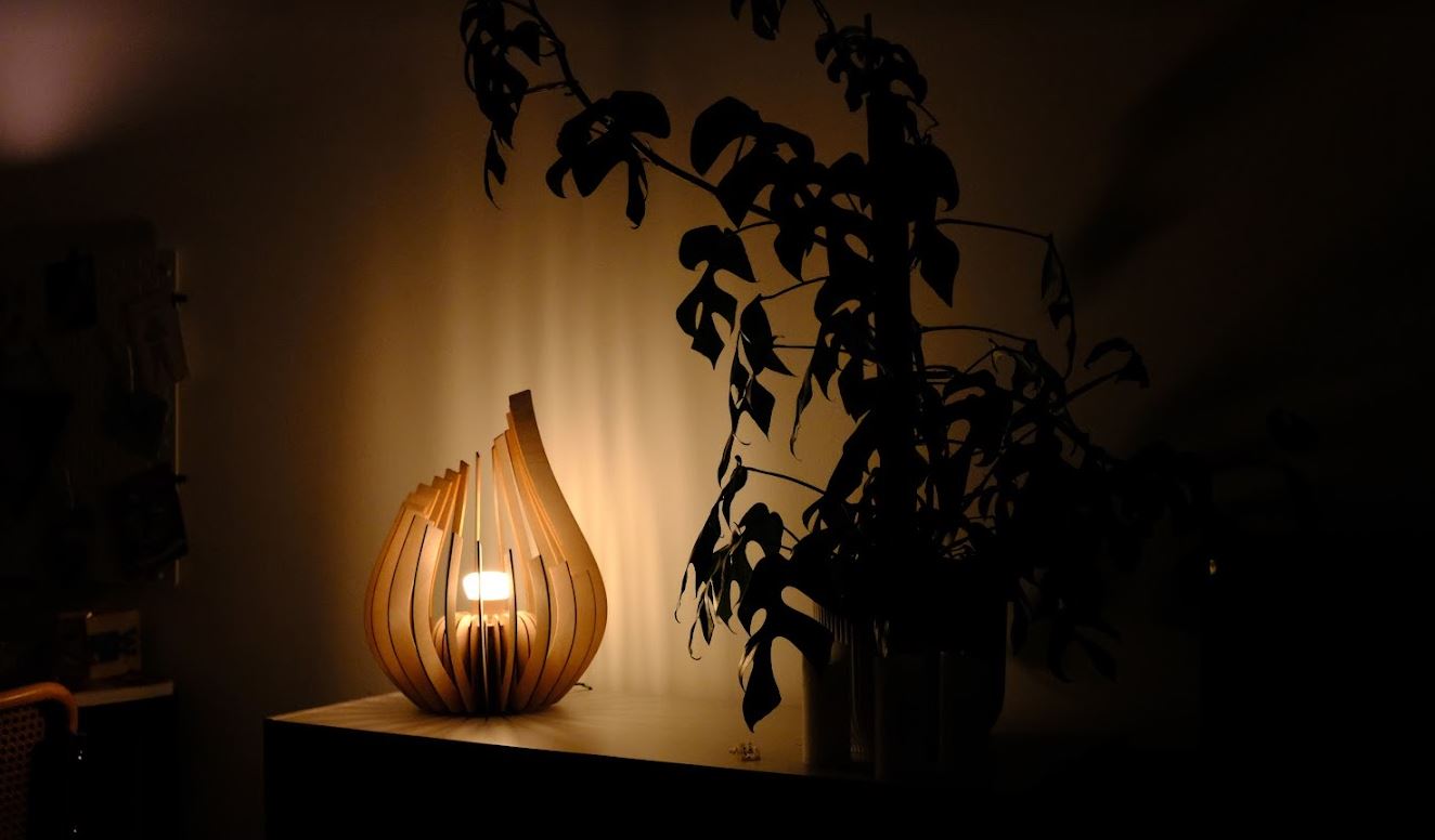 image of the lamp in a dimly lit room, casting gentle light onto the table and wall